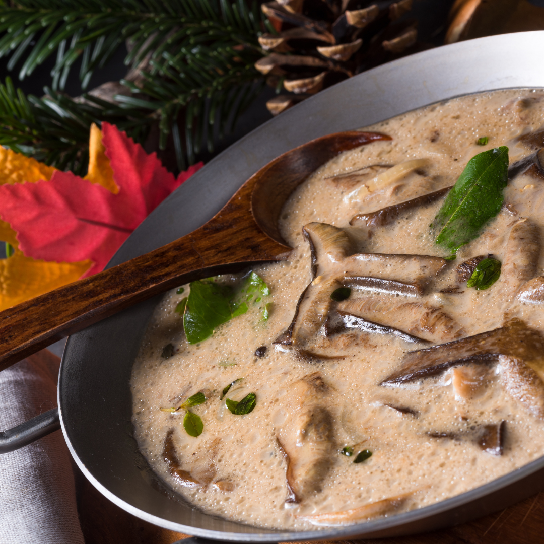 a saucepan with a wooden spoon placed in it artfully displaying a Mushroom broth adorned with herbs.